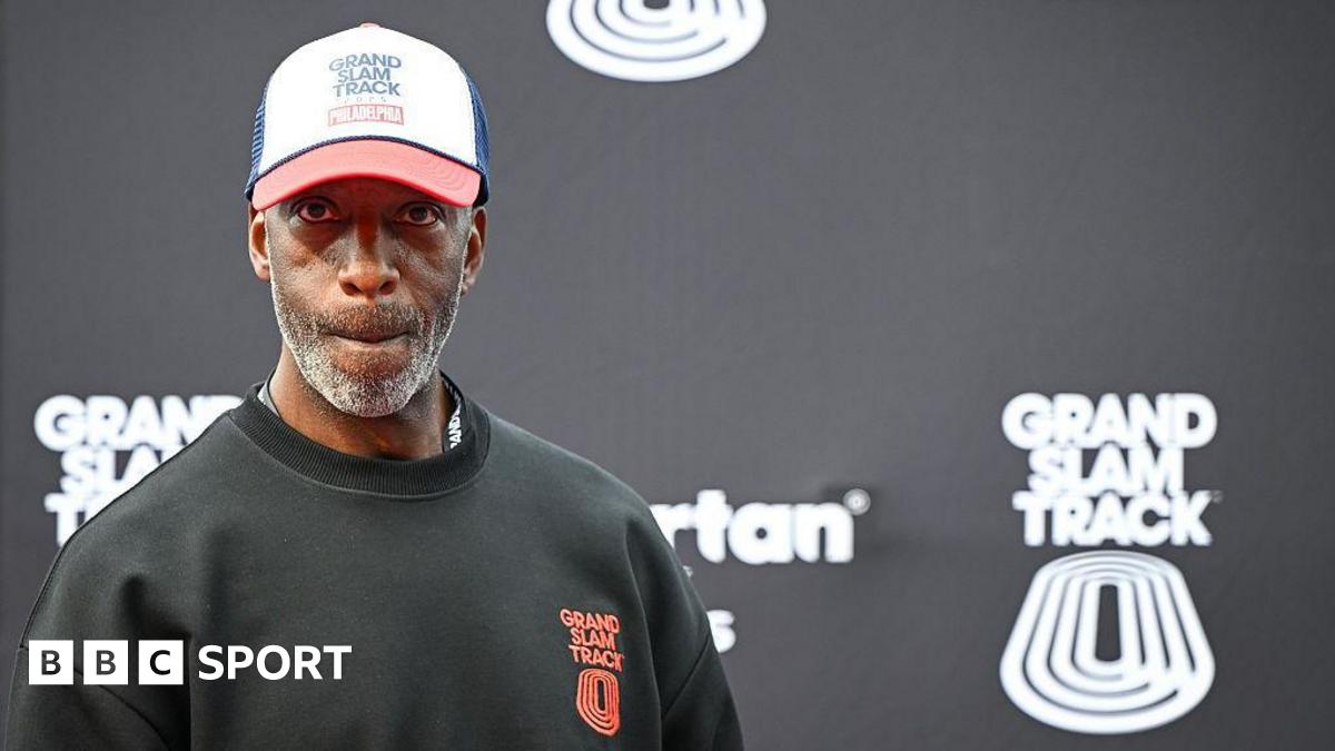 Michael Johnson looking pensive as he stands in front of a black board bearing the Grand Slam Track name and logo