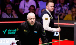 John Higgins eyes a shot