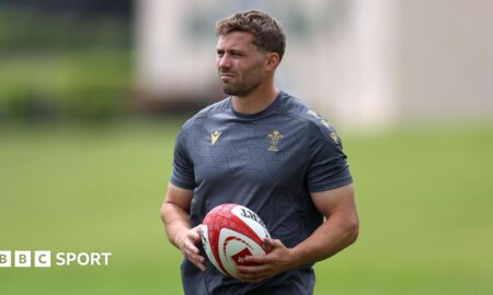 Leigh Halfpenny holds a ball while watching Wales training