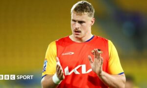 Tom Allen applauds in the red and yellow jersey of Hurricanes