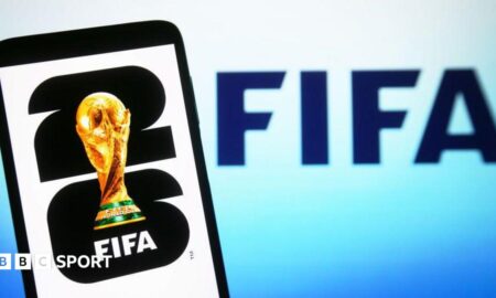 In this illustration, a World Cup 2026 logo is shown on a smartphone screen in front of a Fifa logo
