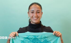 A smiling Jana Fernandez holds a London City shirt